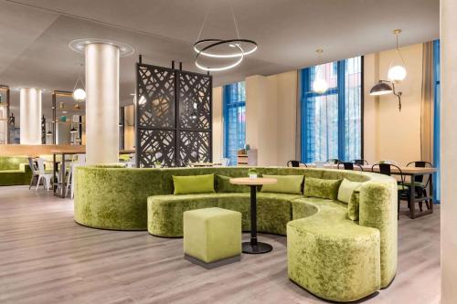 eine Lobby mit einer grünen Couch sowie Tischen und Stühlen in der Unterkunft Super 8 by Wyndham Hamburg Mitte in Hamburg