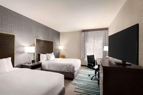 a hotel room with two beds and a flat screen tv at La Quinta by Wyndham Clovis CA in Clovis