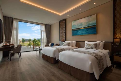 a hotel room with two beds and a large window at Wyndham Grand KN Paradise Cam Ranh in Cam Ranh