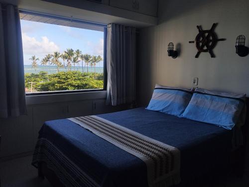 a bedroom with a bed and a window with a view of the ocean at Apartamento Ibiza Vista Mar in Maceió