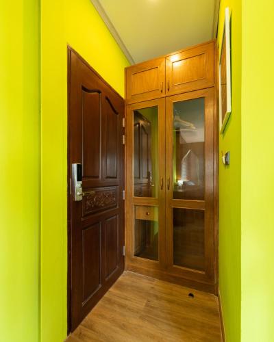 a hallway with a wooden door and yellow walls at Tepbunthom Hostel in Bangkok