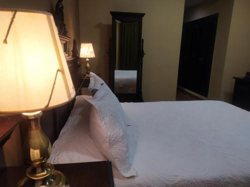 a bedroom with a bed with white sheets and a lamp at Los Bronces in Lucena