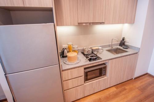 a small kitchen with a refrigerator and a sink at Oakwood Hotel & Residence Sri Racha in Si Racha