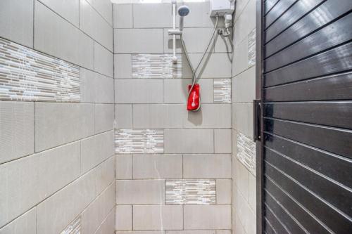 La salle de bains est pourvue d'une douche avec un objet rouge. dans l'établissement RedDoorz Hostel near Stadion Mandala Krida Yogya, à Yogyakarta