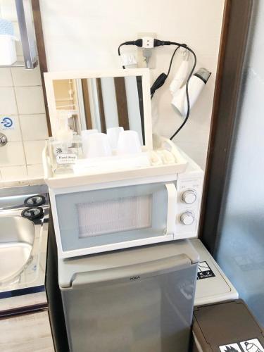 a microwave oven in a room with a sink at ラ・ポート空港前201 in Fukuoka