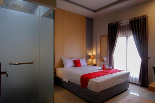 Un dormitorio con una cama con almohadas rojas y una ventana en RedDoorz Syariah @ Jalan Sultan Agung Tegal en Tegal