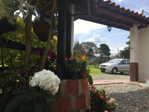a porch with flowers and a car in a parking lot at Casa Hotel Portón Campestre in Jardin