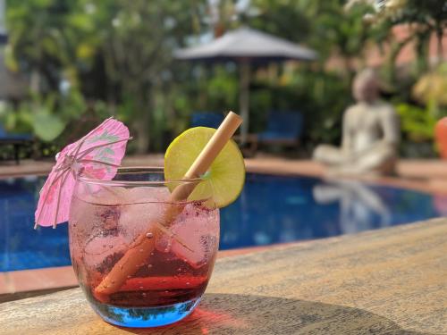 a drink sitting on a table next to a pool at Raingsey Bungalow in Kep