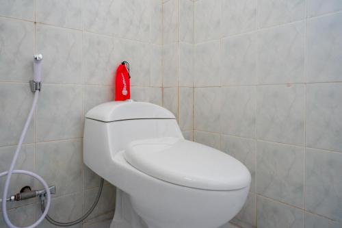 a bathroom with a white toilet with a red bottle on it at RedDoorz @ Hotel Horas Palopo in Palopo