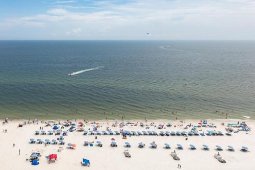 eine Gruppe von Menschen am Strand mit Sonnenschirmen in der Unterkunft Seawind Condominiums in Gulf Shores