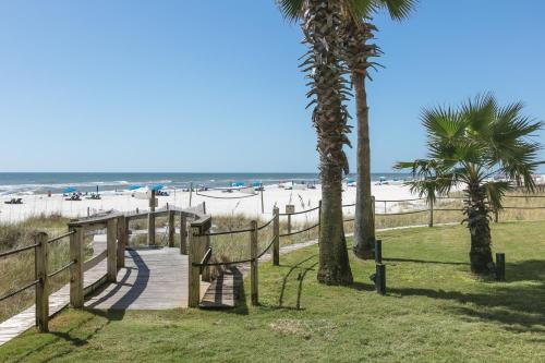 un sentiero in legno che conduce alla spiaggia con palme di Summer House On Romar Beach a Orange Beach