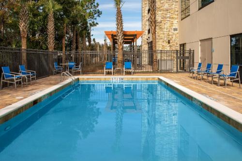 una piscina con sillas azules y un edificio en Holiday Inn Express & Suites Kingsland I-95-Naval Base Area, an IHG Hotel en Kingsland