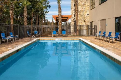 una piscina con sedie blu e un edificio di Holiday Inn Express & Suites Kingsland I-95-Naval Base Area, an IHG Hotel a Kingsland