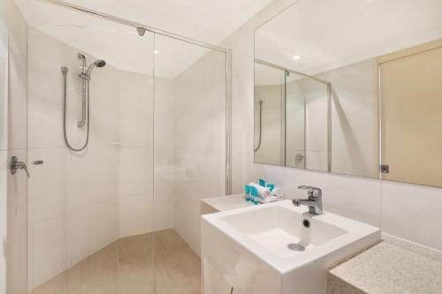 a white bathroom with a sink and a shower at Points North Apartments in Gold Coast