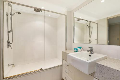 a white bathroom with a sink and a shower at Points North Apartments in Gold Coast