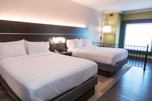 a hotel room with two beds and a large window at Holiday Inn Express Hotel & Suites Columbia-Fort Jackson by IHG in Columbia