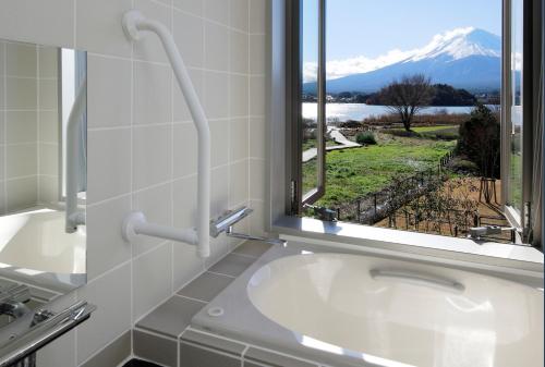 bagno con vasca e finestra con vista di Kawaguchiko Urban Resort Villa a Fujikawaguchiko