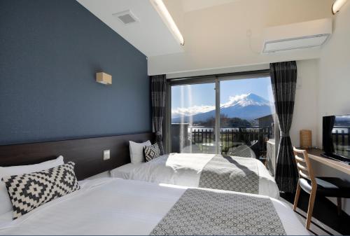 2 letti in una camera da letto con vista sulle montagne di Kawaguchiko Urban Resort Villa a Fujikawaguchiko
