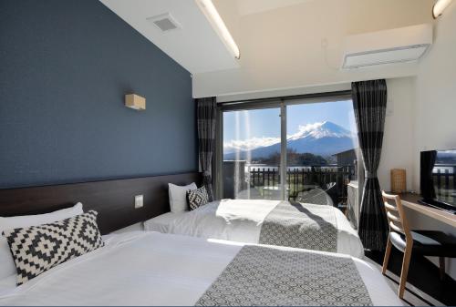 two beds in a bedroom with a view of a mountain at Kawaguchiko Urban Resort Villa in Fujikawaguchiko