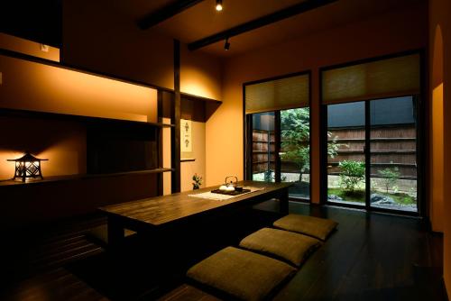 a dining room with a wooden table and windows at Miro Hachijo Genmachi BeTei in Kyoto