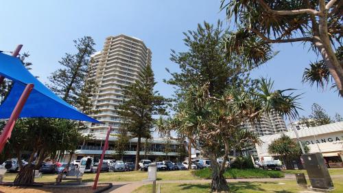 a tall apartment building with cars parked in a parking lot at Points North Apartments in Gold Coast