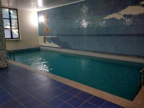a swimming pool in a room with blue tiles at Silk Way Hotel in Aktau