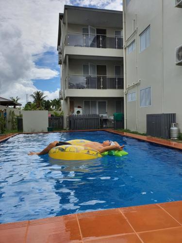 蘇瓦的住宿－FIJI HOME Apartment Hotel，躺在游泳池信息板上的男人