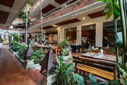 um restaurante com bancos, mesas e plantas em Raming Lodge Hotel em Chiang Mai