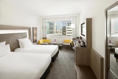 a hotel room with two beds and a desk at Novotel World Trade Centre Dubai in Dubai