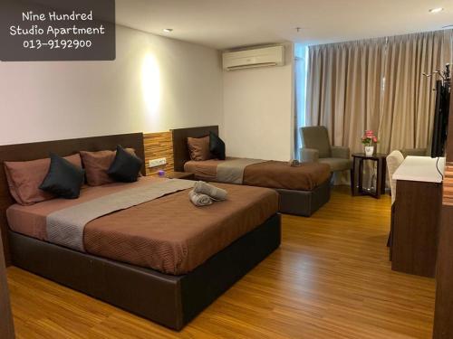 a hotel room with two beds and a chair at Nine Hundred Studio Apartment (KBCP) in Kota Bharu