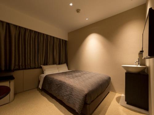 a small bedroom with a bed and a sink at THE HOTELS HAKATA KASANE Bayside in Fukuoka
