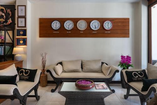 a living room with a couch and clocks on the wall at Lee Chiang Hotel in Chiang Mai