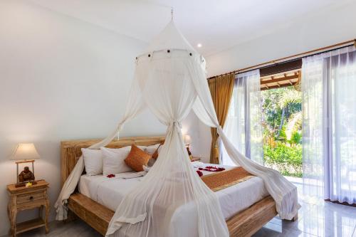 sypialnia z łóżkiem z białą moskitierą w obiekcie Ubud Batan Nyuh bed & breakfast w mieście Ubud