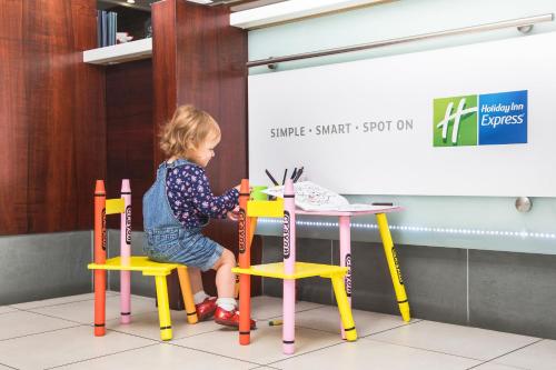 a little girl sitting on a chair at a table at Holiday Inn Express York by IHG in York