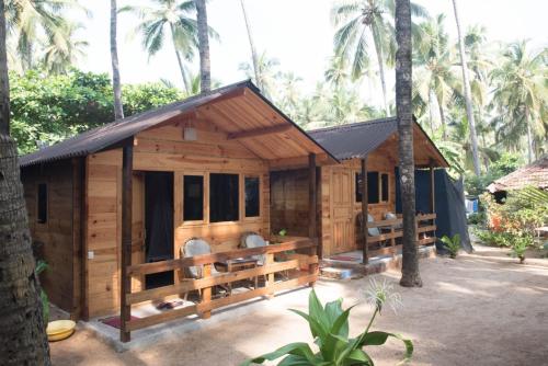 a small wooden house with chairs in front of trees at Magic World in Palolem