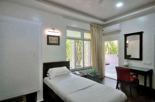a bedroom with a bed and a desk and a window at Hotel Ketan in Pune