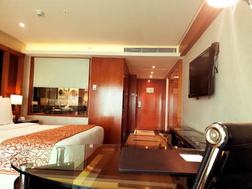 a hotel room with a bed and a glass table at Gokulam Grand Hotel & Spa Bangalore in Bengaluru