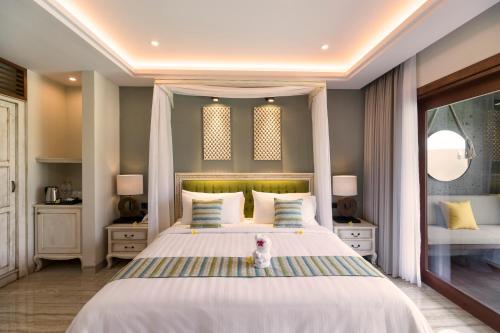 a bedroom with a large bed with a teddy bear standing on it at Sense Canggu Beach Hotel in Canggu
