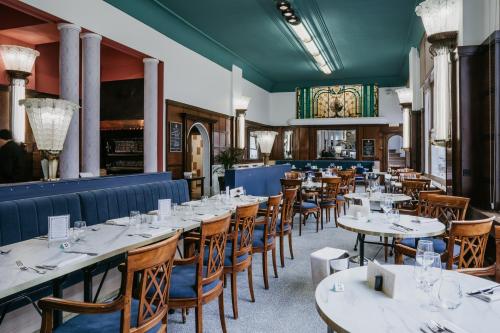 une salle à manger avec des tables et des chaises blanches dans l'établissement Le Grand Hotel, à Valenciennes
