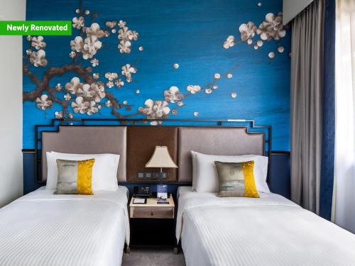 two beds in a hotel room with a blue wall at Copthorne King's Hotel Singapore on Havelock in Singapore