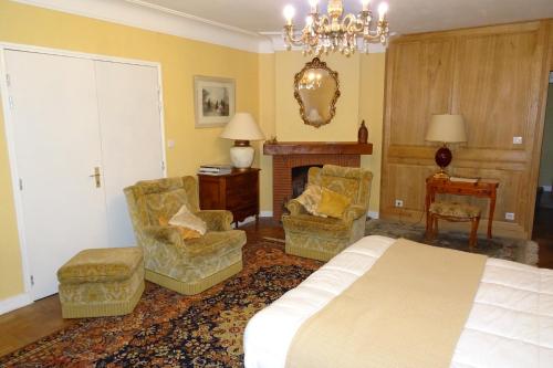 a bedroom with a bed and two chairs and a fireplace at Chambres d'Hôtes à la Fontanille in Panazol