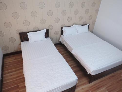 two beds in a small room with white sheets at KHÁCH SẠN HƯƠNG SEN PHÚ YÊN in Tuy Hoa
