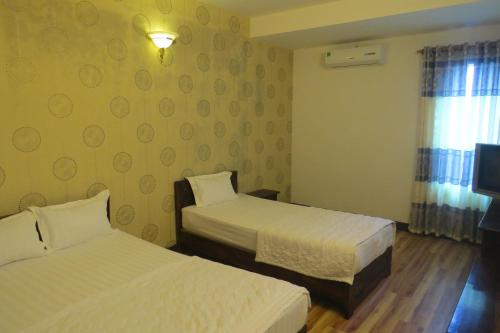a hotel room with two beds and a window at KHÁCH SẠN HƯƠNG SEN PHÚ YÊN in Tuy Hoa