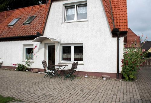 uma mesa e cadeiras em frente a uma casa branca em Ferienwohnungen auf dem Pommernhof em Samtens