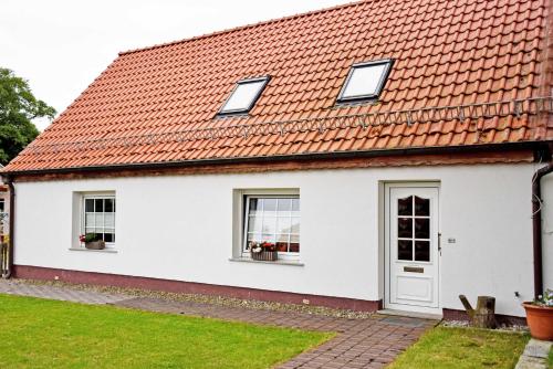 een wit huis met een oranje dak bij Ferienwohnungen auf dem Pommernhof in Samtens