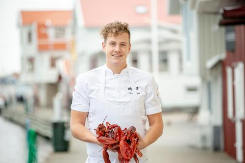 a man in a chefs uniform holding a lobsters at Stora Hotellet i Fj&auml;llbacka in Fj&auml;llbacka