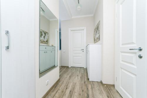 un couloir avec une porte blanche et un miroir dans l'établissement Лучшая квартира в Броварах, à Brovary