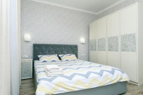 Schlafzimmer mit einem Bett mit einer blauen und weißen Bettdecke in der Unterkunft Лучшая квартира в Броварах in Browary