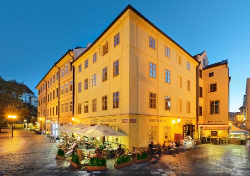 a large yellow building with people sitting outside of it at Hotel Lippert in Prague