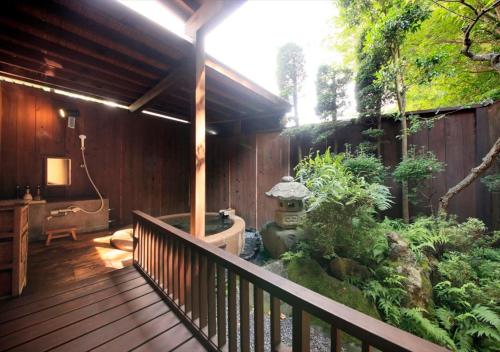 a deck with a bath tub and a garden at Saikatei Jidaiya in Kaminoyama